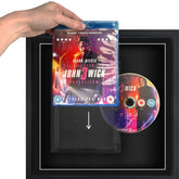 A person holding a blu-ray DVD movie sliding it into a plastic protective case, in a frame.