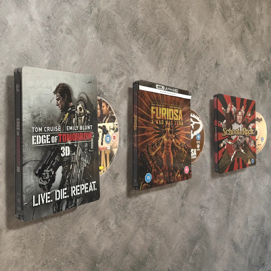 Collection of movie steelbooks and discs displayed on a textured grey surface without brackets or supports
