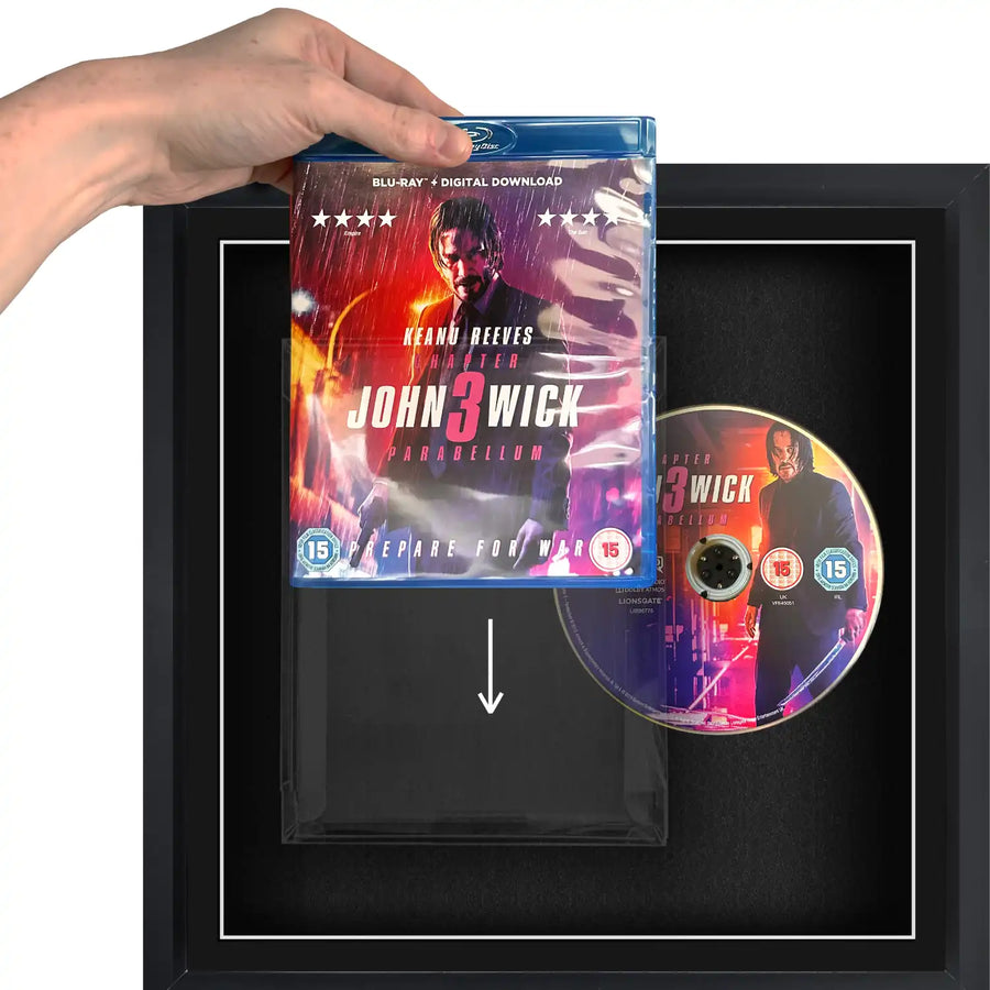 A person holding a blu-ray DVD movie sliding it into a plastic protective case, in a frame.