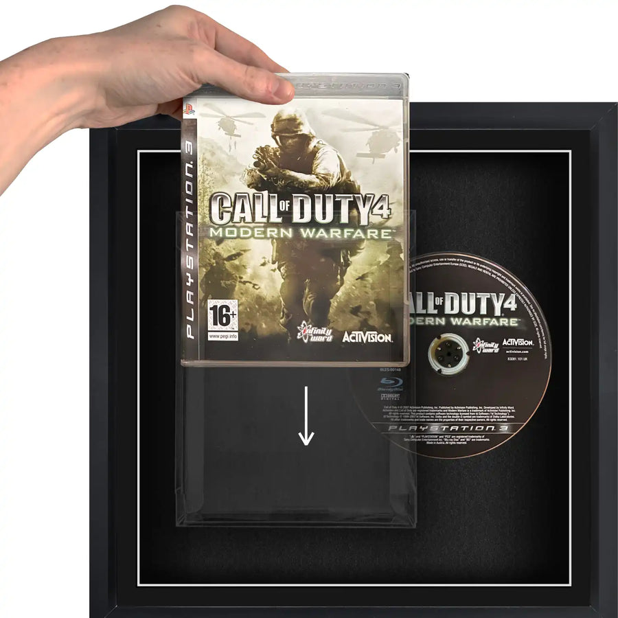A person holding a Playstation 3 (PS3) video games sliding it into a plastic protective case, in a frame.