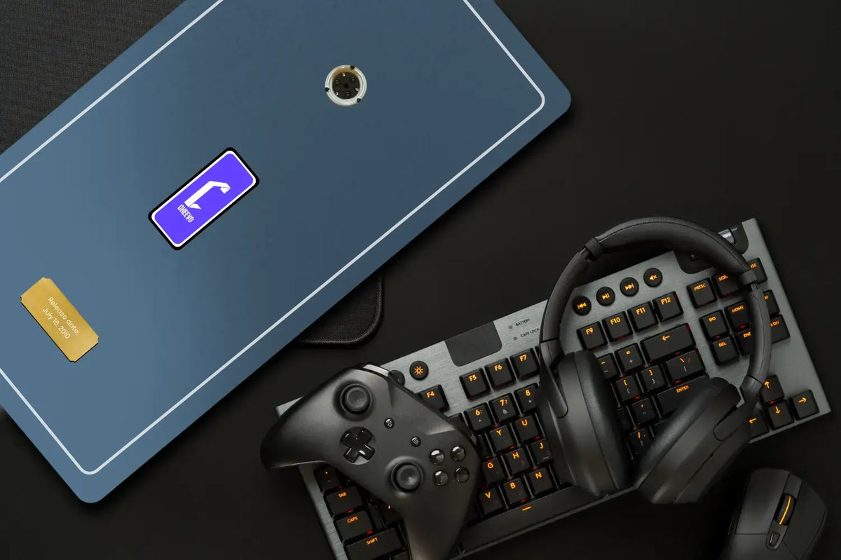 A dark blue rectangular plate with a DVD spindle and a purple Cheevo logo, styled on a black desk alongside a mechanical keyboard, black headphones, a game controller, and a mouse.