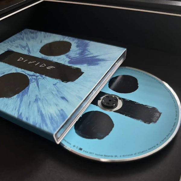 Divide music CD with its illustrated blue sleeve and matching light blue disc, displayed inside a black box.