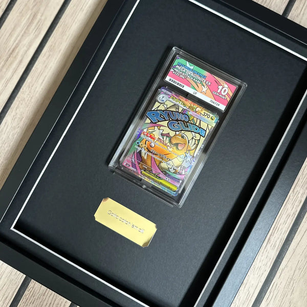 A framed collectible display featuring a graded card in a clear plastic slab mounted on a black mat inside a black shadowbox frame, with a small gold plaque below. The comic card shows colourful cartoon artwork and a grading label at the top.