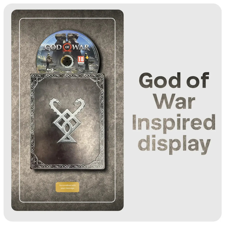 Product packaging for 'God of War' inspired display with game disc and decorative emblem.