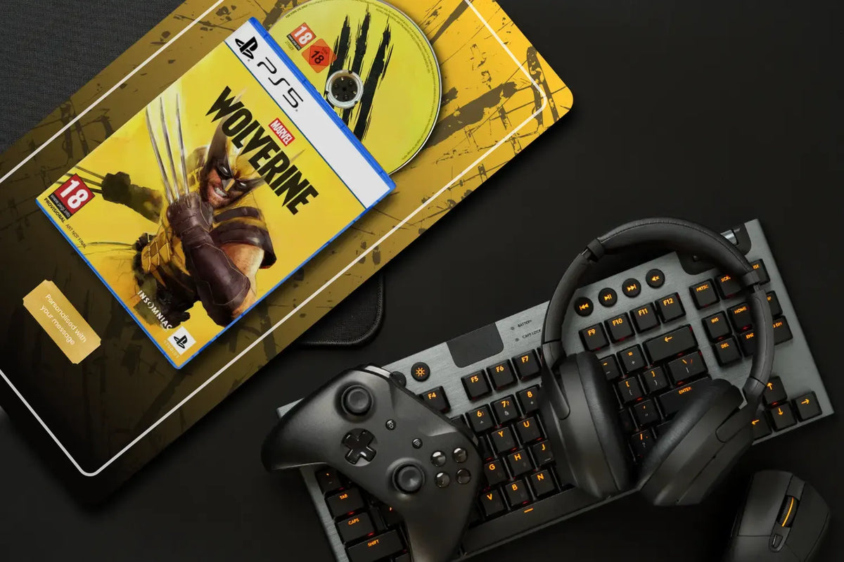 A PlayStation 5 game bundle featuring Marvel's Wolverine, styled on a dark surface with a mechanical keyboard, wireless controller, and over-ear headphones.