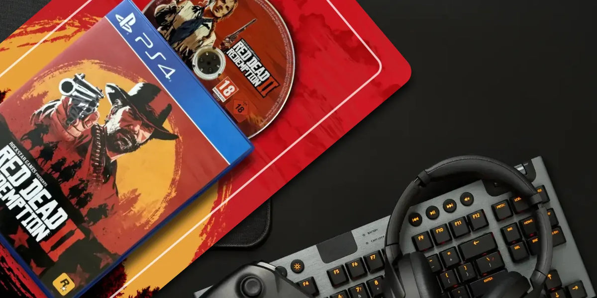 PS5 game bundle featuring Red Dead Redemption II, including the game case, disc, and a red branded sleeve, styled on a dark surface with a keyboard, headset, and controller nearby.
