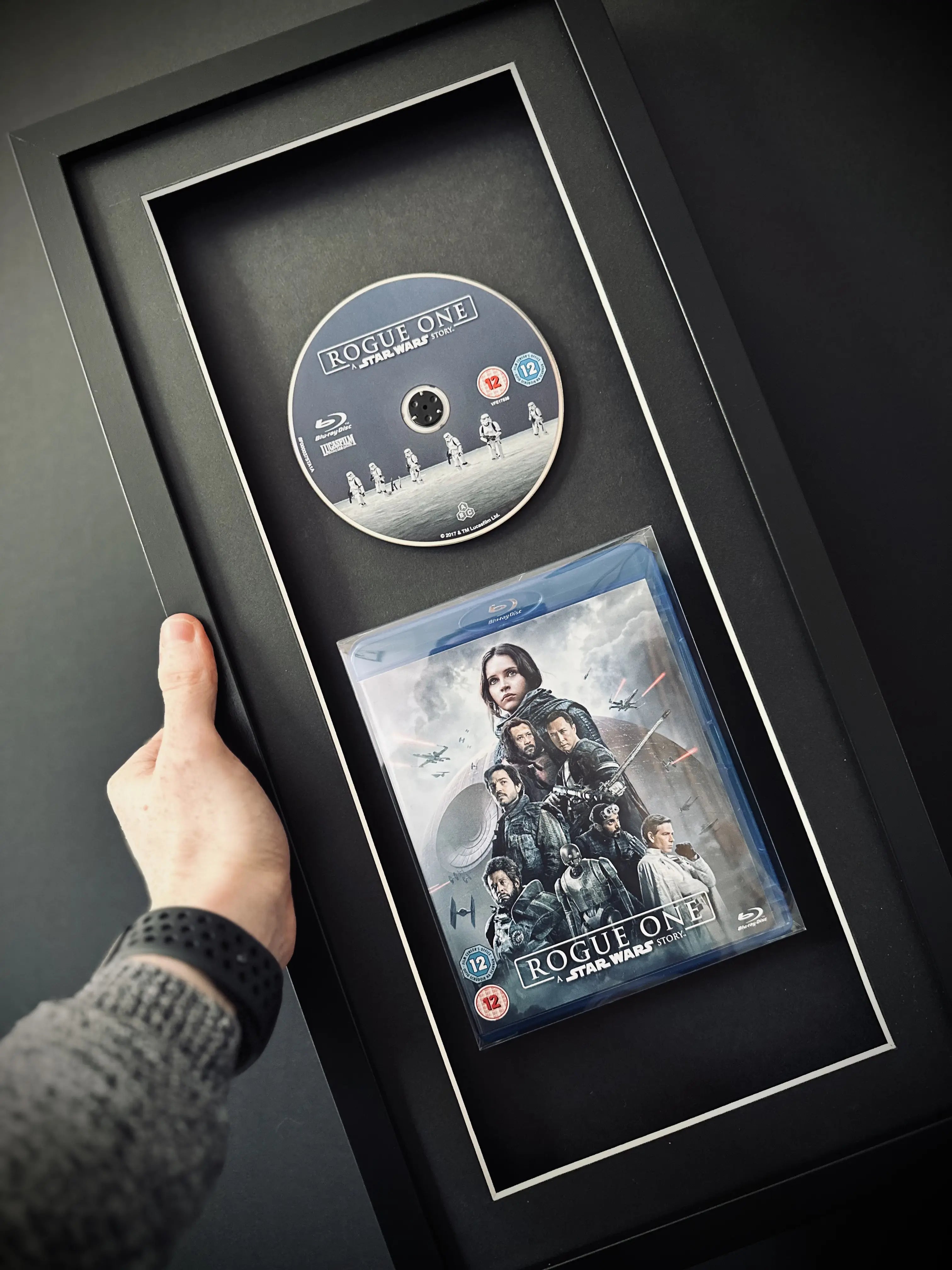 Wall-mounted Star Wars Rogue One Blu-ray in a sleek black portrait frame featuring UV protection, perfect for creating a cinematic display at home.