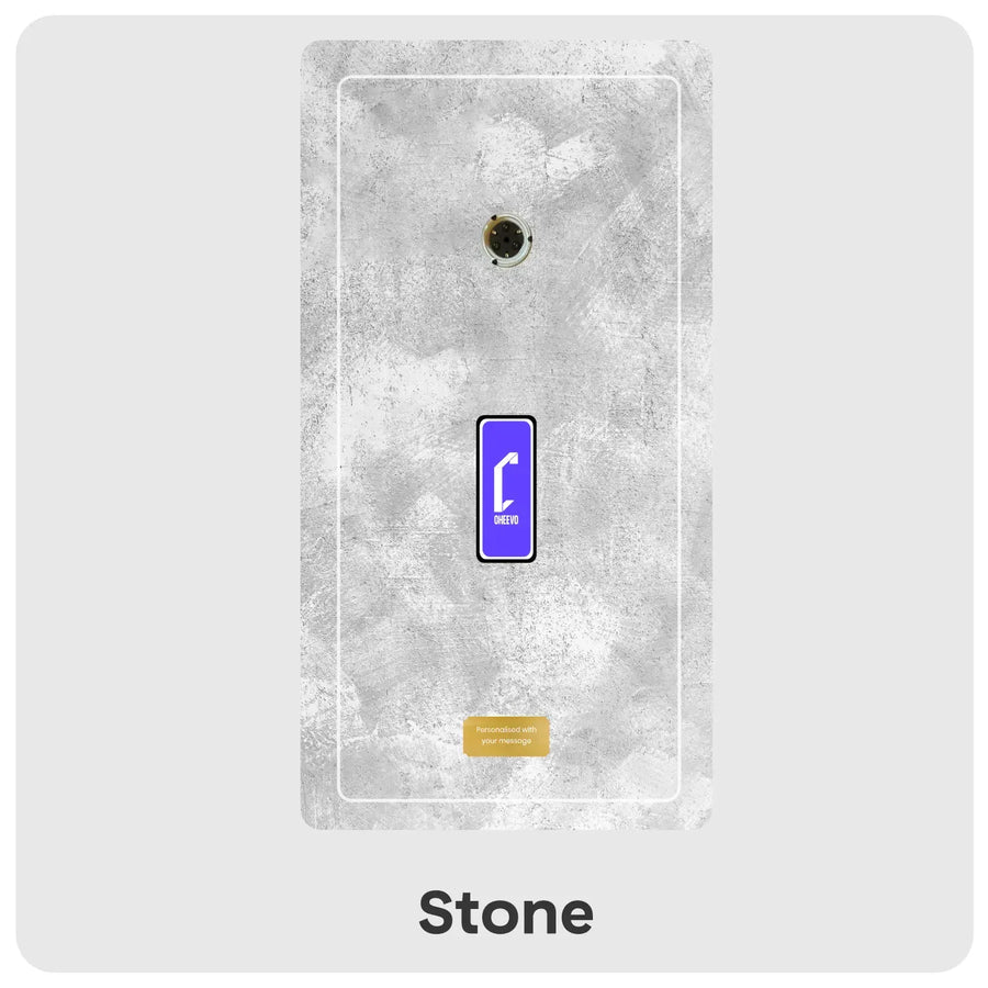 A rectangular wall-mounted panel in a stone texture finish, shown against a light grey background. The panel has a faux concrete look with a small circular opening near the top, a blue-and-white Cheevo icon in the center, and a small gold label near the bottom.