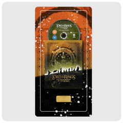 Lord of the Rings: The Fellowship of the Ring 3D Blu-ray and DVD box set in a decorative display plate, featuring a green DVD-R disc, a gold and black jewel case, and an orange and black outer sleeve with white speckled details.
